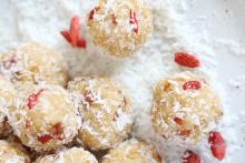 apricot coconut lime protein balls on a bed of coconut snow speckled with goji berries, looking really yummy